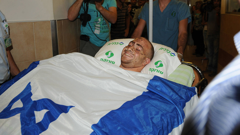 Ziv Shilon, cubierto por la bandera de Israel tras sufrir un atentado. 