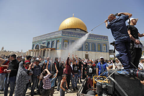 Un hombre rocía con agua fresca a los palestinos congregados en la Explanada de las Mezquitas. Atrás, la Cúpula de la Roca. 