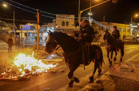 Fuego y caballos de la policía en una calle de Jerusalem. 