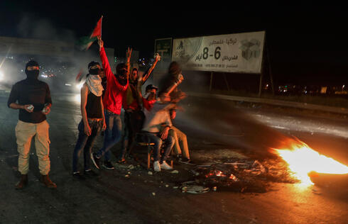 Manifestantes palestinos queman neumáticos en el puesto de control de Hawara, durante los enfrentamientos ocurridos en Jerusalem el sábado por la noche.