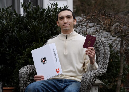 Noah Rohrlich, cuyo abuelo huyó del nazismo en Austria, posa en su casa con su certificado de ciudadanía y un nuevo pasaporte de Austria. 