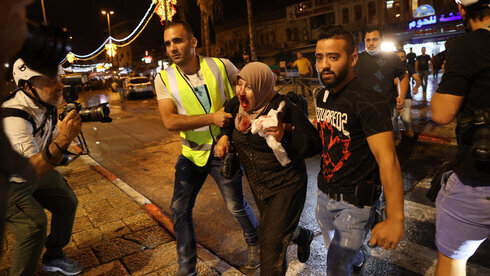 Dos hombres ayudan a una palestina que resultó herida durante los enfrentamientos.