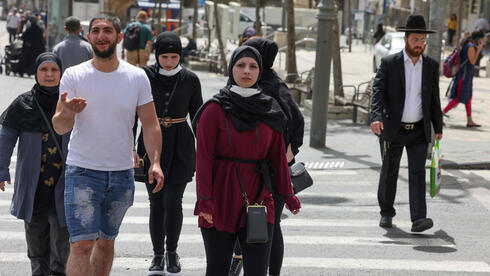 Israelíes caminan por Jerusalem sin cubrirse el rostro con mascarillas.