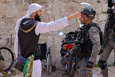 Un manifestante palestino discute con un policía israelí.