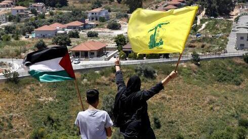 Militantes libaneses ondean sendas banderas de Palestina y Hezbollah, cerca de la ciudad israelí de Metula, en la frontera entre Líbano e Israel. 