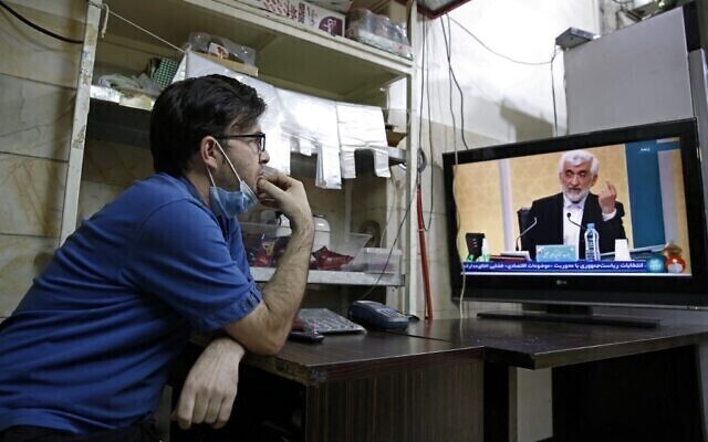 Un ciudadano iraní mira al candidato Saeed Jalili durante el primer debate preelectoral en una tienda de Teherán. 