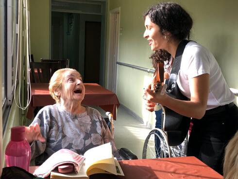 Lucía Abelar canta para una residente de un hogar de ancianos antes de la pandemia.