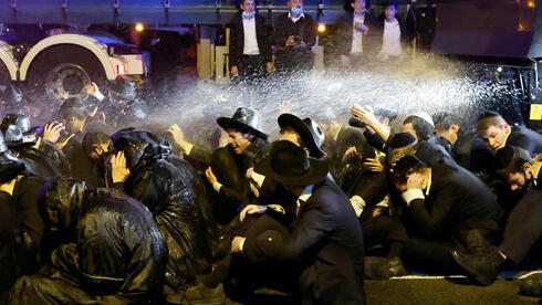 Manifestantes ultraortodoxos alcanzados por chorros de agua lanzados por la policía en una protesta contra el reclutamiento para las FDI. 
