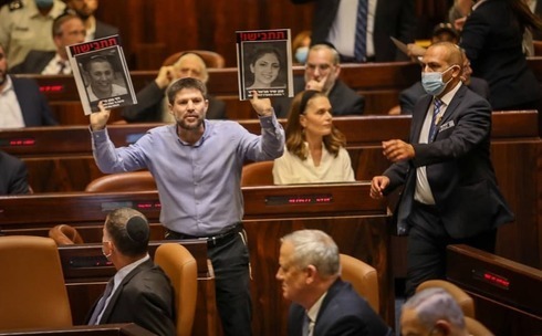 Bezalel Smotrich, líder de Sionismo Religioso, muestra fotos de víctimas del terrorismo durante el discurso de Bennett en la Knesset el domingo. 