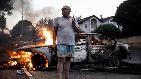Un residente de Lod junto a su automóvil en llamas durante los disturbios en Lod en mayo.