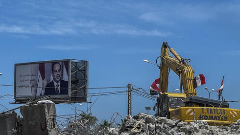 Una excavadora limpia los escombros en Gaza junto a una imagen del presidente egipcio Abdel Sisi, que ha prometido millones de dólares para reconstruir el enclave. 