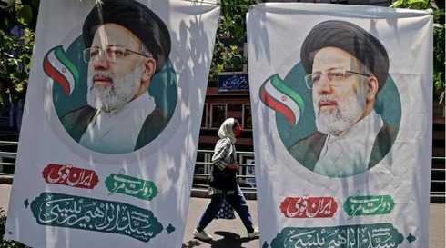 Una iraní pasa entre dos afiches del candidato presidencial Ebrahim Raisi, el 17 de junio de 2021 en Teherán. 