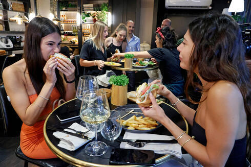 Los comensales en Ness Ziona comen hamburguesas de pollo cultivado. (AFP ) Los comensales en Ness Ziona comen hamburguesas de pollo cultivado.