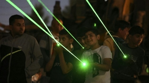 Jóvenes y niños apuntan con rayos láser contra las ventanas de las viviendas judías del asentamiento de Eviatar. 