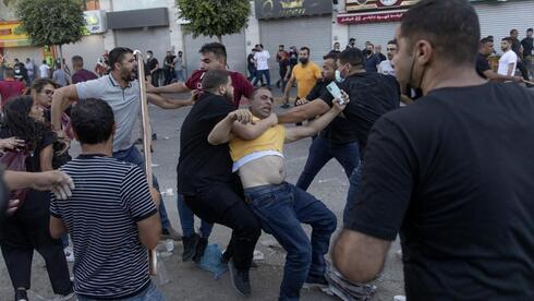Agentes de seguridad palestinos detienen a un manifestante durante una protesta en Ramala por la muerte del crítico de la AP, Nizar Banat. 