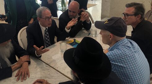 Nachman Shai, segundo desde la izquierda, habla con el senador Rick Scott, de gorra, en el Grand Beach Hotel de Surfside, Florida.