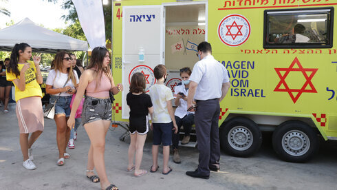 Adolescentes hacen cola frente a un centro de vacunación emergente en Tel Aviv.