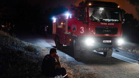 Un bombero utiliza su teléfono móvil en la aldea de Vavatsina, en el distrito de Larnaca, mientras continúan los esfuerzos para controlar un gigantesco incendio forestal.