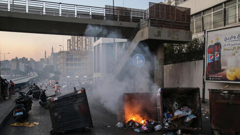 Manifestantes queman contenedores de basura para bloquear una carretera que conduce al aeropuerto en Beirut. 