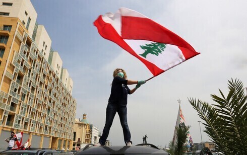 Una mujer libanesa ondea la bandera nacional durante las protestas contra el gobierno en Beirut, abril de 2021. 