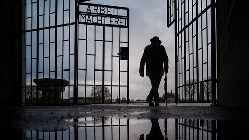Un hombre atraviesa la puerta del campo de exterminio nazi de Sachsenhausen con la frase "Arbeit macht frei" (el trabajo te hace libre) en Oranienburg, Alemania. 