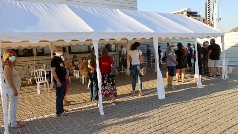 Una fila de personas esperando para recibir la tercera vacuna.