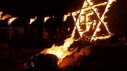 Una estrella de David de madera con una cruz esvástica en el centro en llamas tras ser prendida fuego por manifestantes palestinos cerca del asentamiento Eviatar, en Cisjordania.