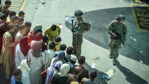 Soldados estadounidenses frente a ciudadanos afganos que intentan huir del país en el aeropuerto de Kabul.