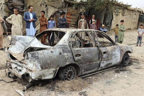 Gente mirando un vehículo dañado por un ataque con un cohete en Kabul, Afganistán. 