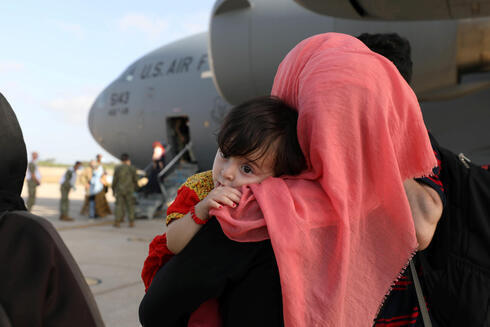 Una mujer afgana llega con su hijo a Kuwait tras ser evacuada de Afganistán por las fuerzas estadounidenses.