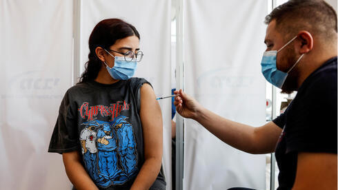 Una joven recibe una dosis de refuerzo contra el coronavirus en una clínica de Tel Aviv, 