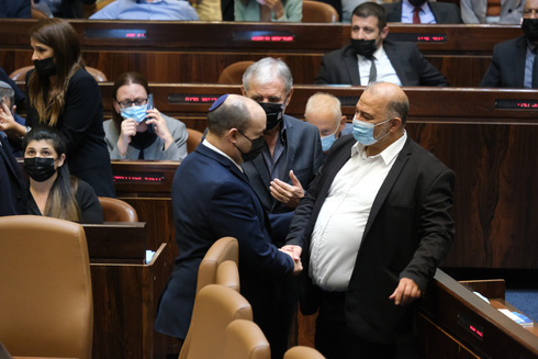 El primer ministro Naftali Bennett y el jefe de Ra'am, Mansour Abbas, se dan la mano durante la sesión en la Knesset. 