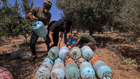 Palestinos enmascarados organizan botes de gas mientras preparan globos incendiarios para volar hacia Israel. 