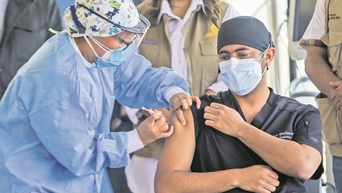 En Honduras, un trabajador de la salud inocula a un  paciente con la vacuna de Moderna. 
