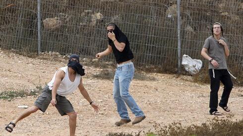 Colonos israelíes arrojan piedras a casas palestinas en la ciudad de Hebrón en Cisjordania. 