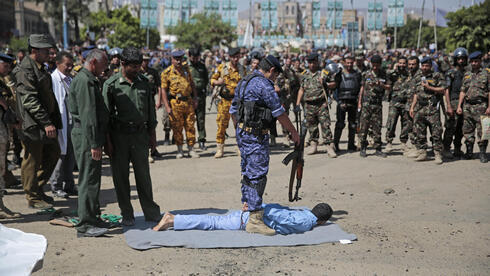 Un hombre en el piso, junto a su verdugo. Fue condenado por estar involucrado en el asesinato de un alto funcionario hutí: Ocurrió el sábado 18 de septiembre, en la plaza Tahrir en Sanaa, Yemen. 