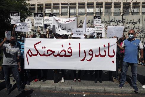 Clientes sostienen una pancarta en árabe que dice: "Pandora (Papers) te expuso", durante una protesta frente al Banco Central en Beirut. 