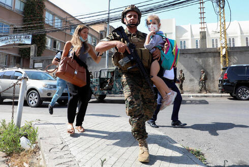 Un soldado libanés ayuda a civiles a evacuar la zona.