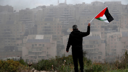 Un manifestante ondea una bandera palestina durante una manifestación cerca del asentamiento de Modi'in Ilit en Cisjordania. 
