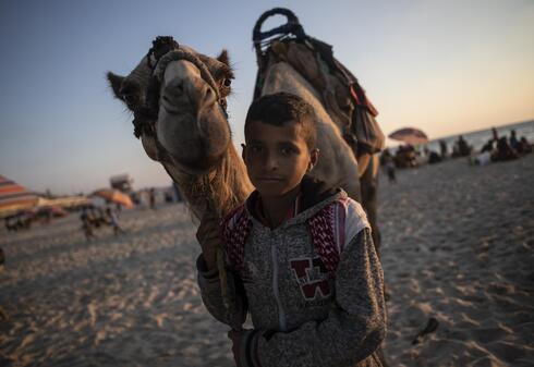 Un niño palestino posa para una foto junto a su camello en la playa de la Ciudad de Gaza. 