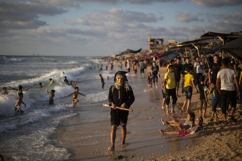 Un joven palestino con una máscara camina por la playa de la ciudad de Gaza. 