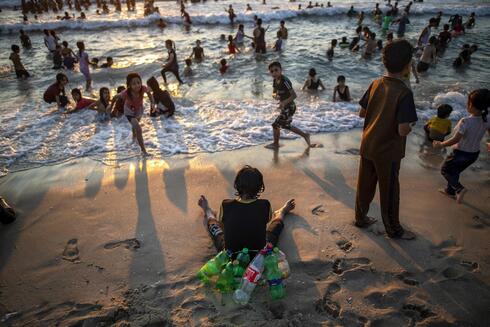 Un niño palestino usa botellas vacías para flotar mientras nada en Gaza. 