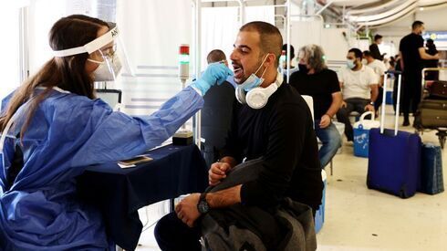 Un trabajador de la salud toma una muestra de hisopo de un viajero para una prueba de enfermedad por coronavirus en el Aeropuerto Internacional Ben Gurion. 