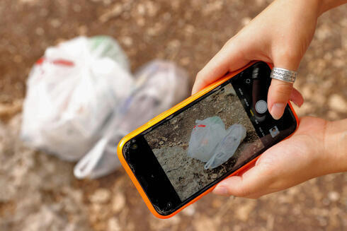 Elishya Ben Meir tomando una foto de la basura que recogió a través de Clean Coin. 