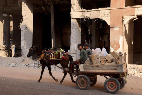 Palestinos viajan en un carro de caballos que transporta escombros. 