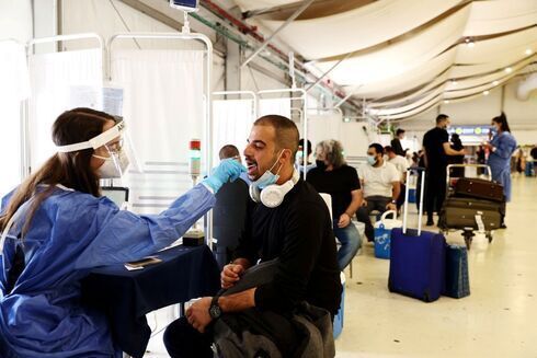  Un trabajador de la salud toma una muestra de hisopo de un viajero para una prueba de coronavirus en el Aeropuerto Internacional Ben-Gurion. 