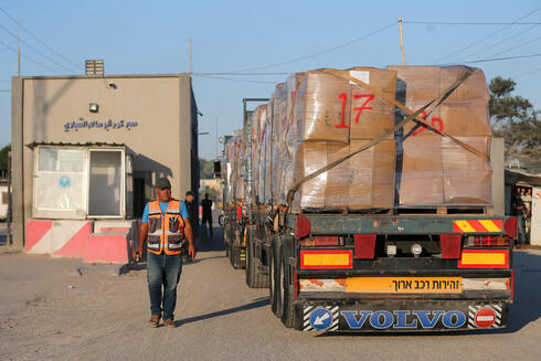 Hombre palestino junto a un camión que transporta ropa para la exportación, en el cruce de Kerem Shalom en Rafah, en el sur de la Franja de Gaza. 