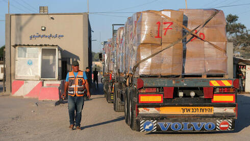 Hombre palestino junto a un camión que transporta ropa para la exportación, en el cruce de Kerem Shalom en Rafah, en el sur de la Franja de Gaza. 
