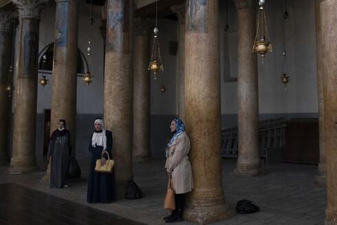 Turistas posan para una foto apoyadas en columnas restauradas de la Iglesia de la Natividad. 