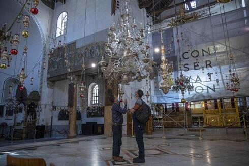 Turistas visitan la Iglesia de la Natividad, en Belén, Cisjordania, y observan una de las arañas que fueron restauradas. 